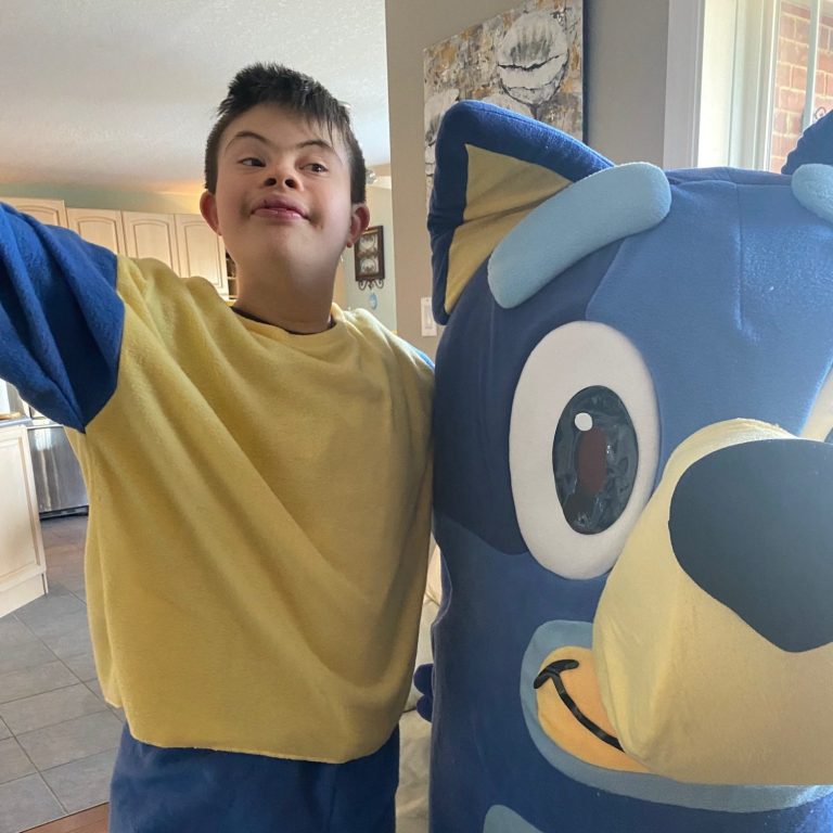 Young boy happily showing his blue and yellow mascot outfit