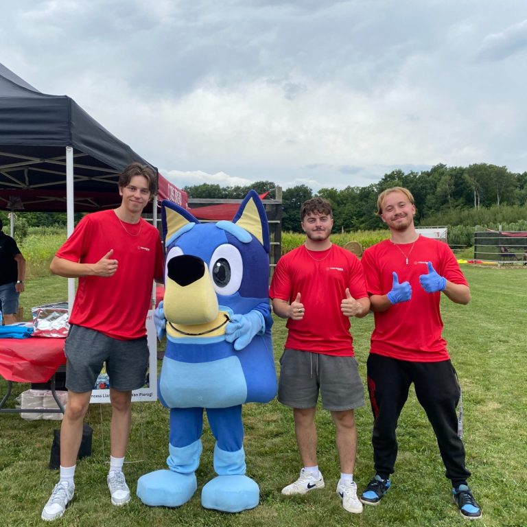 Yellow and blue dog costume worn by young teenager. A woman is standing beside him smiling.
