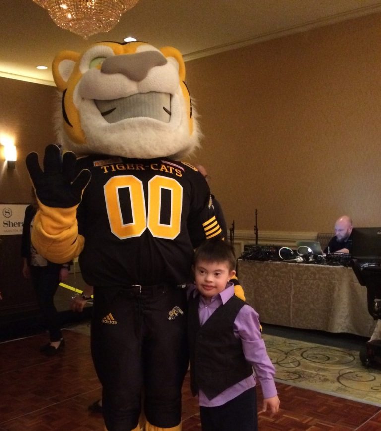 Photo of Tiger Cats Mascot with a little boy to his side. 